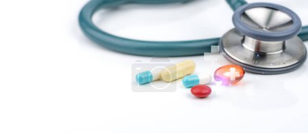 Photo for Tablet and capsule pills with stethoscope on white background. Healthcare and medicine concept. Prescription drugs, vitamins, minerals, and dietary supplements. Medical equipment for health checkup. - Royalty Free Image