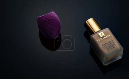 Téléchargez les photos : CHONBURI, THAÏLANDE-15 DÉCEMBRE 2022 : Eponge de maquillage Jovina et fond de teint Estee Lauder. Fond de teint beige liquide et mélangeur beauté sur fond noir. - en image libre de droit