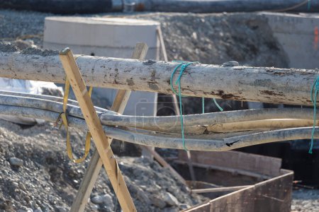 The supporting of pipes using rope and wood on a construction site.