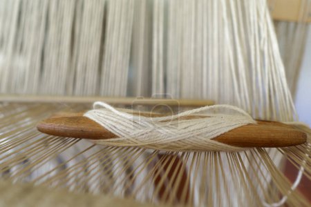A shuttle for textile work with string under tension.