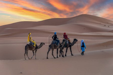 Téléchargez les photos : Trois passagers et leur manutentionnaire voyagent dans le désert du Sahara au Maroc - en image libre de droit