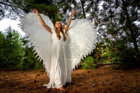 Foto de Una hermosa modelo rubia posa al aire libre mientras usa un conjunto de alas blancas para Halloween. - Imagen libre de derechos