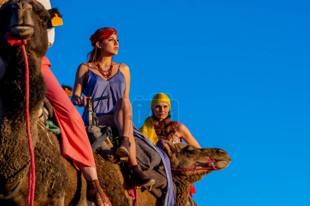 Photo for A beautiful model rides a camel through the Saharan Desert in Morocco - Royalty Free Image