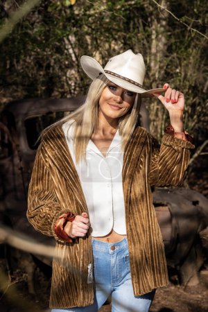 Foto de A gorgeous blonde cowgirl model poses outdoors while enjoying the spring weather - Imagen libre de derechos