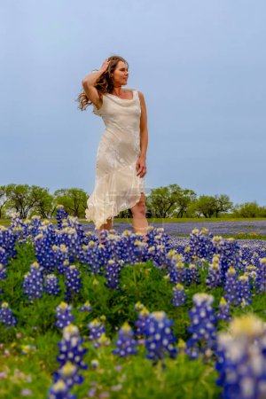 Foto de Una hermosa modelo morena disfruta de un campo de flores Bluebonnet en un día de primavera - Imagen libre de derechos