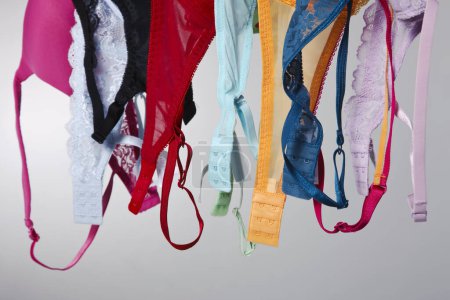 A group of colorful bras hang on a clothes line in a studio environment