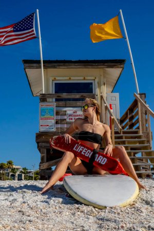 An attractive lifeguard, positioned strategically along the coastline, diligently surveying the beaches, with her watchful eyes poised to detect any indications of swimmers in distress.
