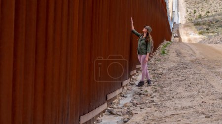 Téléchargez les photos : Un migrant désespéré traverse le mur frontalier de Jacumba, cherchant à entrer illégalement aux États-Unis, soulignant les défis de l'immigration en cours - en image libre de droit