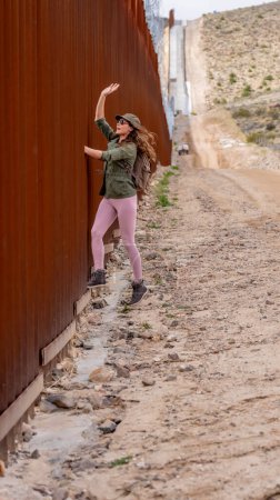Téléchargez les photos : Un migrant désespéré traverse le mur frontalier de Jacumba, cherchant à entrer illégalement aux États-Unis, soulignant les défis de l'immigration en cours - en image libre de droit