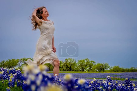 Foto de Una hermosa modelo morena disfruta de un campo de flores Bluebonnet en un día de primavera - Imagen libre de derechos