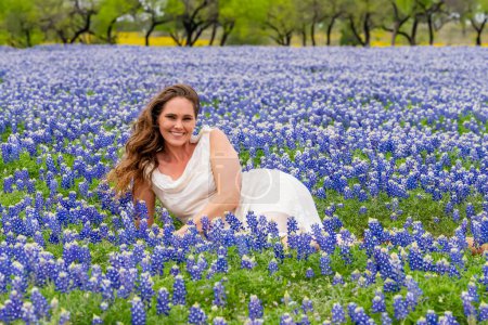 A beautiful brunette model enjoys a field of Bluebonnet flowers on a spring day