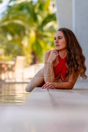 Joven belleza disfruta del sol caribeño junto a la piscina, saboreando un oasis vacacional de calidez, relajación y felicidad pura