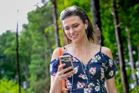 Eine brünette Studentin, in ihr Handy vertieft, geht flott zum Unterricht und navigiert nahtlos durch das Campus-Leben