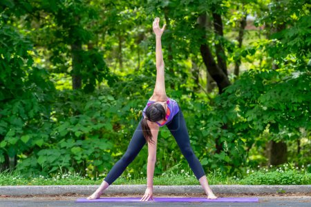 Au milieu de l'agitation du campus, une étudiante brune sereine trouve la tranquillité grâce au yoga, s'arrêtant gracieusement des cours pour une pause rajeunissante