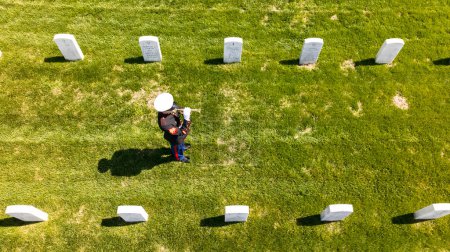 A poignant moment unfolds as a Marine plays taps, honoring a fallen veteran with a solemn salute, marking their internment at a national military cemetery.