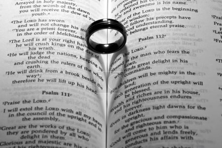 Symbolische Vereinigung: Hochzeitsband ruht auf dem Buch der Mormonen, wirft einen herzförmigen Schatten und verkörpert Liebe, Ehre und Engagement.