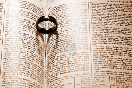 Symbolische Vereinigung: Hochzeitsband ruht auf dem Buch der Mormonen, wirft einen herzförmigen Schatten und verkörpert Liebe, Ehre und Engagement.