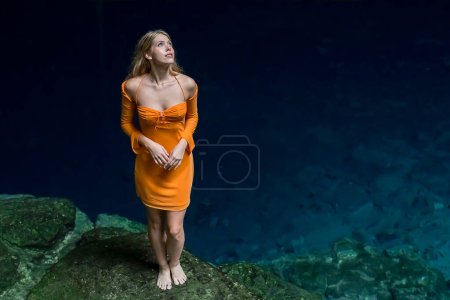 In Cuzama, Yucatan, Mexico, a stunning model revels in the vibrant hues of a cenote's blue and green waters, creating a picturesque scene of natural beauty.