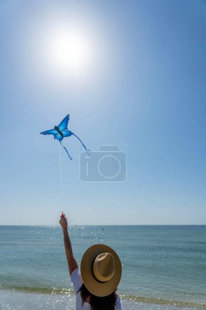 Une belle mannequin brune mature profite d'une journée à la plage tout en volant son cerf-volant près du rivage