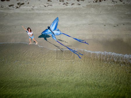 Ein schönes reifes brünettes Model genießt einen Tag am Strand, während sie ihren Drachen in Küstennähe fliegt