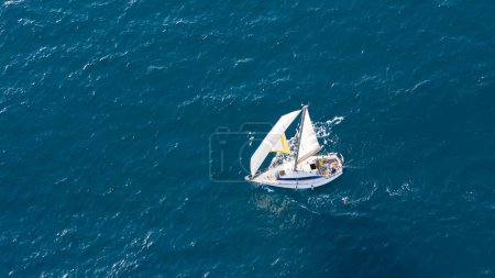 Ein kleines Segelboot gleitet auf klaren Mittelmeergewässern in der Nähe von Malaga, Spanien, unter einem ruhigen Sommerhimmel.