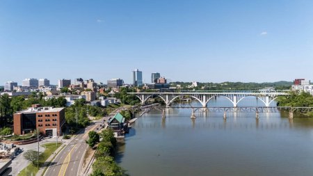 Téléchargez les photos : Une vue aérienne de Knoxville, Tennessee révèle un paysage urbain dynamique avec un mélange de bâtiments historiques et modernes, la rivière Tennessee tissant à travers le centre-ville, parcs verdoyants luxuriants, et les lointaines montagnes fumées encadrant l'horizon. - en image libre de droit