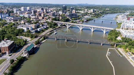 Photo for An aerial view of Knoxville, Tennessee reveals a vibrant cityscape with a mix of historic and modern buildings, the Tennessee River weaving through downtown, lush green parks, and the distant Smoky Mountains framing the horizon. - Royalty Free Image