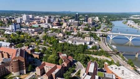 Photo for An aerial view of Knoxville, Tennessee reveals a vibrant cityscape with a mix of historic and modern buildings, the Tennessee River weaving through downtown, lush green parks, and the distant Smoky Mountains framing the horizon. - Royalty Free Image