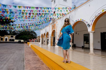 A stunning young traveler explores Telchec, Mexico's vibrant streets, basking in colorful architecture and breathtaking scenery, capturing memorable poses.