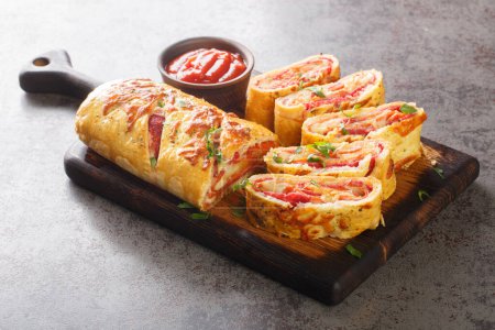 Hot Italian stromboli roll stuffed with salami sausage and mozzarella cheese close-up on a wooden board on the table. horizonta
