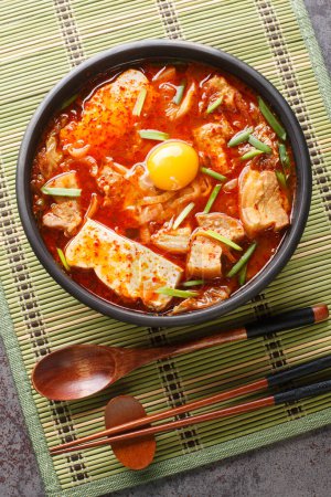 Photo for Sundubu Jjigae Spicy Kimchi Soft Tofu Stew closeup on the bowl on the table. Vertical top view from abov - Royalty Free Image