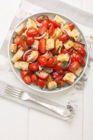 Photo for Puglian acquasala recipe is a perfect summer dish, a salad comprised of torn stale bread soaked in olive oil and tomato closeup on the plate on the table. Vertical top view from abov - Royalty Free Image