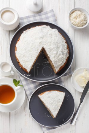 Photo for Boston bun, also known as a Sally Lunn, is a large spiced bun with a thick layer of coconut icing closeup on the table. Vertical top view from abov - Royalty Free Image