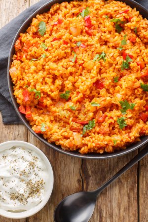 Turkish style bulgur pilaf is a classic hearty and healthy side dish close-up in a bowl on a wooden table. Vertical top view from abov