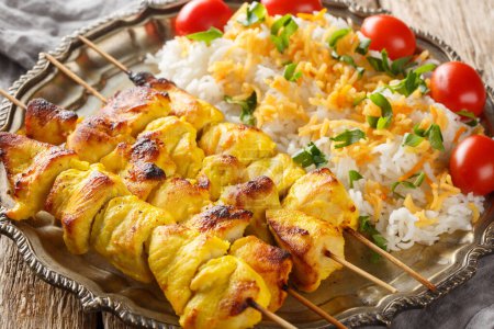 Photo for Grilled saffron chicken skewers with rice garnish close-up in a plate on a wooden table. horizonta - Royalty Free Image