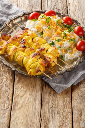 Gegrillter Hähnchenspieß ist als Jujeh Kabab mit Reisnahaufnahme auf dem Teller auf dem Tisch bekannt. Vertica