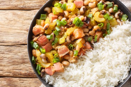 Photo for Hoppin John of black-eyed peas, bacon, sausages, vegetables and scallions with rice closeup on the plate on the wooden table. Horizontal top view from abov - Royalty Free Image