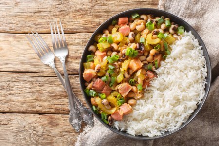Photo for Hoppin John or Carolina peas and rice, is a black-eyed peas and rice with vegetables dish closeup on the plate on the wooden table. Horizontal top view from abov - Royalty Free Image