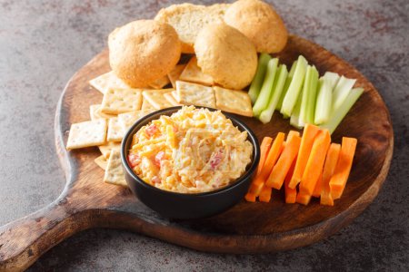 Photo for Homemade Pimento Cheese Dip with carrots, celery and crackers, side view closeup on the wooden board on the table. Horizonta - Royalty Free Image