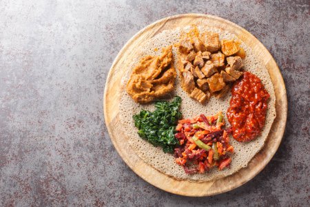 Foto de Etiopía Injera rematado con carne, verduras, verduras de cerca en el tablero de madera sobre la mesa. Vista superior horizontal desde arriba - Imagen libre de derechos