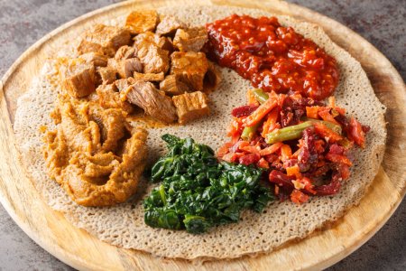 Pan plano de Injera etíope con varios rellenos de verduras y carne de cerca en el tablero de madera sobre la mesa. Horizonta