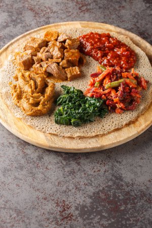 Foto de Comida que consiste en injera y varios tipos de guiso wat o tsebhi es típico de la cocina etíope primer plano en la tabla de madera. Vertica - Imagen libre de derechos