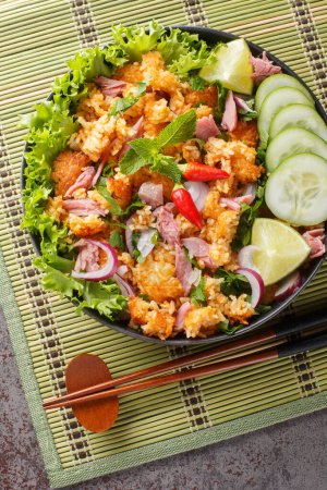 Photo for Laotian Nam Khao Crispy Rice Salad closeup on the plate on the table. Vertical top view from abov - Royalty Free Image