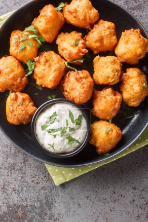 Photo for Deep-Fried Southern Cornmeal Hush Puppies served with tartar sauce closeup on the plate on the table. Vertical top view from abov - Royalty Free Image
