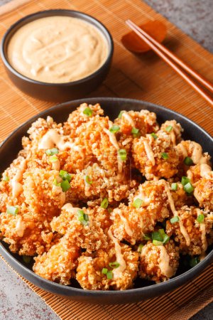 Photo for Crispy fried panko breaded chicken chunks with bang bang sauce, and green onion closeup on the plate on the table. Vertica - Royalty Free Image