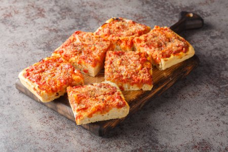 Photo for Sfincione typical oven-baked focaccia very soft and seasoned with tomato, onion, anchovies, cheese, oregano and bread crumbs closeup on the wooden board on the table. Horizonta - Royalty Free Image