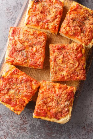 Photo for Italian Sicilian focaccia Sfincione with tomato, onion, anchovies, cheese, oregano and bread crumbs closeup on the wooden board on the table. Vertical top view from abov - Royalty Free Image
