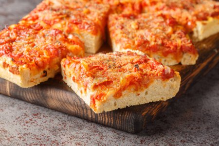 Sizilianische sfincione italienische Pizza Focaccia Brot mit Zwiebeln, Tomatensauce, Sardellen, Caciocavallo-Käse und Semmelbrösel in Großaufnahme auf dem Holzbrett auf dem Tisch zubereitet. Horizonta