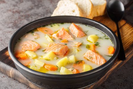 Téléchargez les photos : Soupe de poisson crémeuse avec saumon, pommes de terre, oignons, carottes, aneth et céleri en gros plan sur une assiette sur la table. Horizonta - en image libre de droit