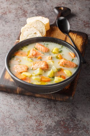 Téléchargez les photos : Soupe de poisson rouge crémeuse aux légumes sur une assiette servie avec du pain en gros plan sur la table. Vertica - en image libre de droit